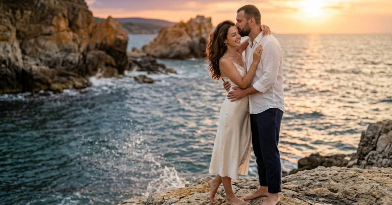 Влюбена двойка се прегръща на скалист бряг при залез – Любов и партньорство на HappyWoman.bg