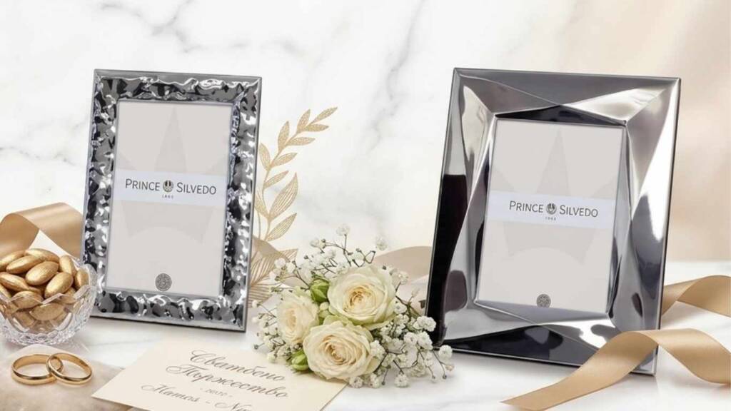 Две сребърни рамки с марка Prince Silvedo, поставени до бели рози и брачни халки – елегантен подарък за сватба.